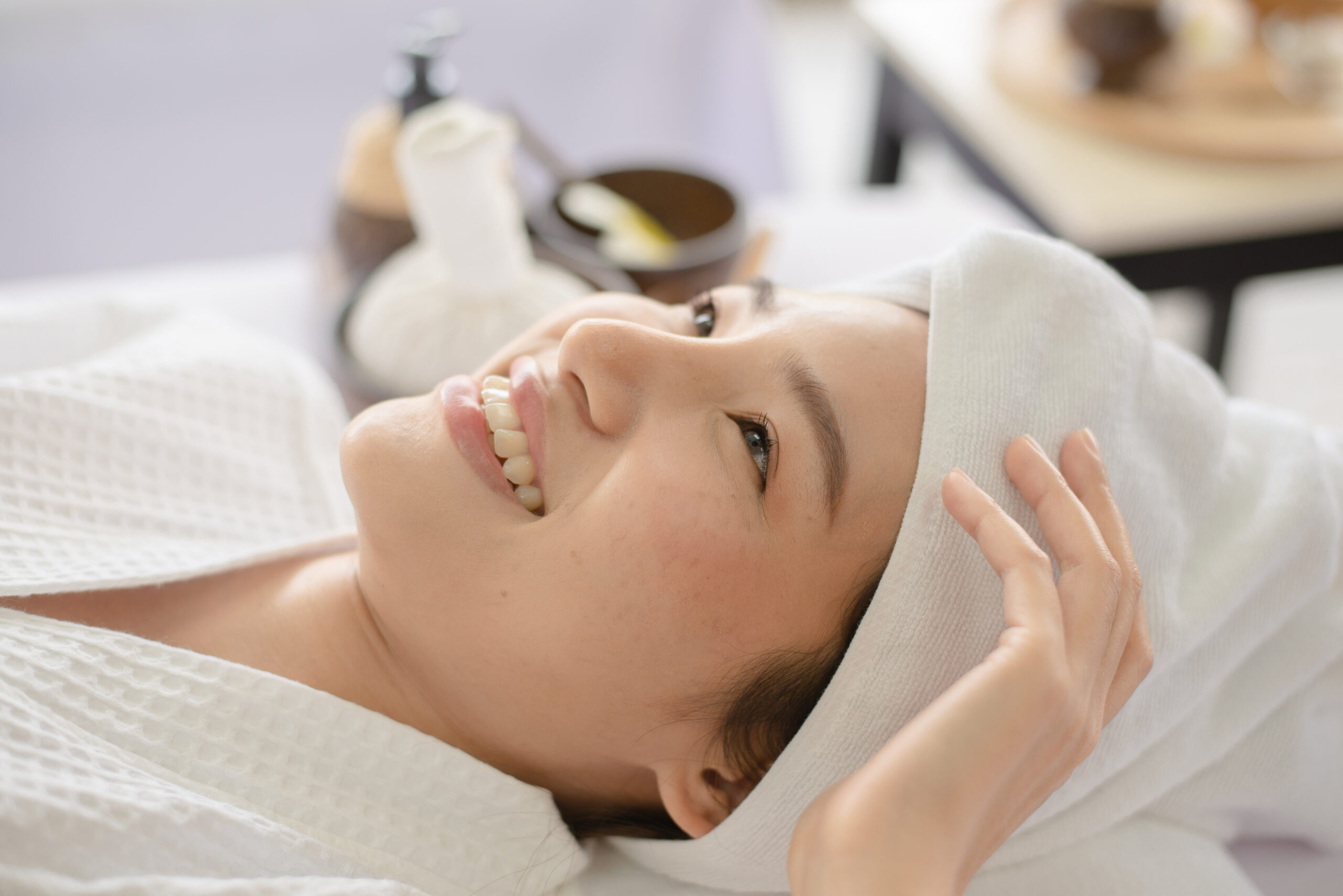 Woman smiling while having a face treatment